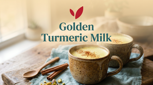 Two ceramic mugs of golden turmeric almond milk garnished with saffron and pistachios, viewed from above on a rustic wooden board.