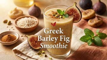 Greek Barley Fig Smoothie - thick creamy beige-gold smoothie in a tall clear glass garnished with a fresh fig slice, mint leaf, cinnamon dusting and chopped pistachios, with dried figs and pearl barley alongside